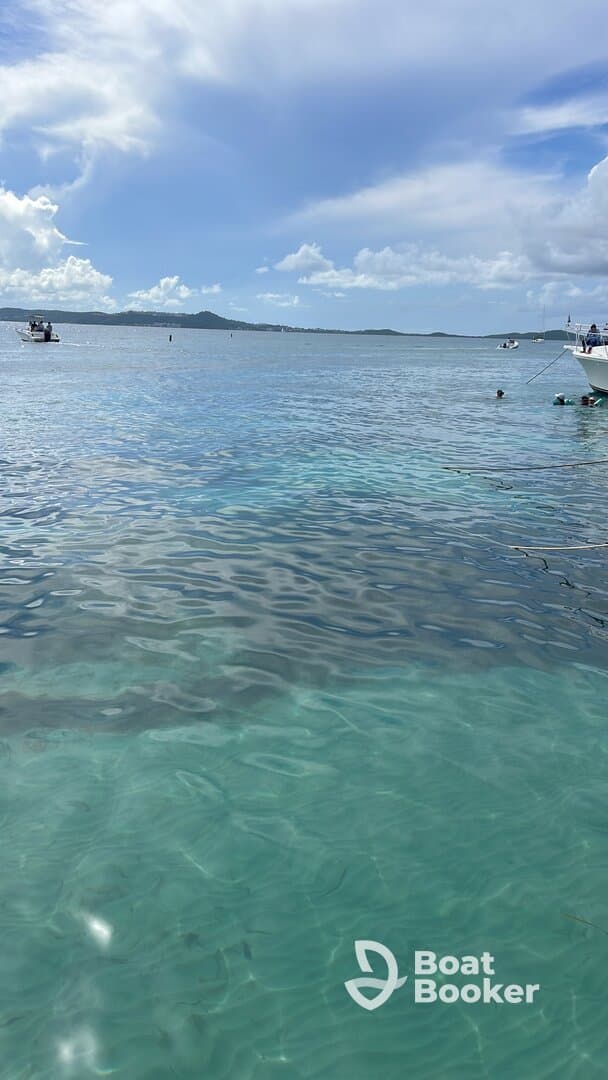 A picturesque view of clear turquoise waters with boats in the background, capturing the essence of a perfect day on the water.