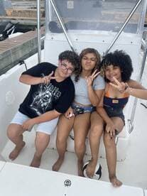 Three friends pose playfully on a boat, capturing a fun moment together — perfect for celebrating adventures on the water.