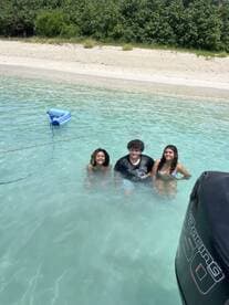 A joyful group of friends enjoys a refreshing swim in crystal-clear waters, perfect for beach outings and summer fun.