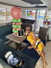 A woman celebrates her 65th birthday inside a beautifully decorated boat cabin, complete with balloons and a festive sign — perfect for memorable celebrations on the water.