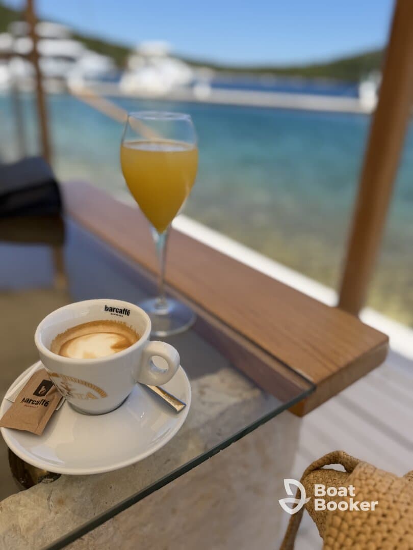 A refreshing mimosa and a cup of coffee set against a stunning waterfront backdrop — perfect for enjoying leisurely moments on a boat trip.
