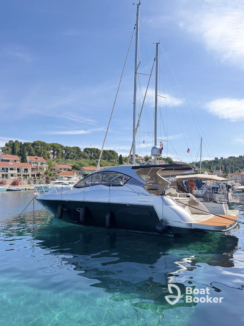 A sleek yacht docked in clear waters, showcasing its elegant design against a picturesque coastal backdrop.