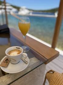 A refreshing mimosa and a cup of coffee set against a stunning waterfront backdrop — perfect for enjoying leisurely moments on a boat trip.