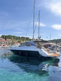 A sleek yacht docked in clear waters, showcasing its elegant design against a picturesque coastal backdrop.