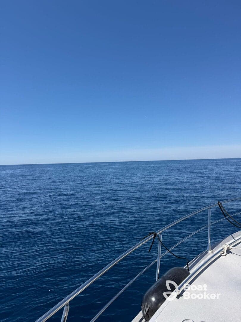 A serene view from the deck of a boat, showcasing the vast blue ocean and clear skies — perfect for a peaceful day on the water.
