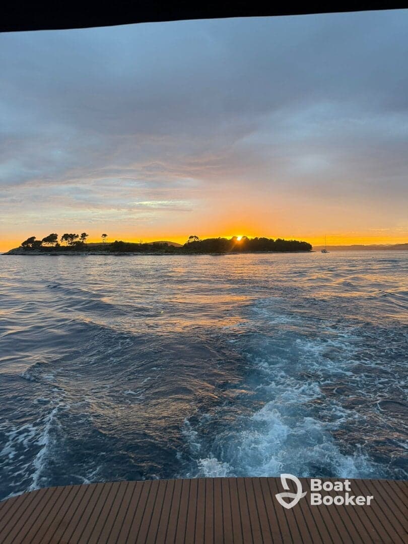 A stunning sunset view from a boat, showcasing the tranquil waters and an island silhouette in the background — perfect for capturing serene moments on the water.