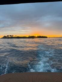 A stunning sunset view from a boat, showcasing the tranquil waters and an island silhouette in the background — perfect for capturing serene moments on the water.