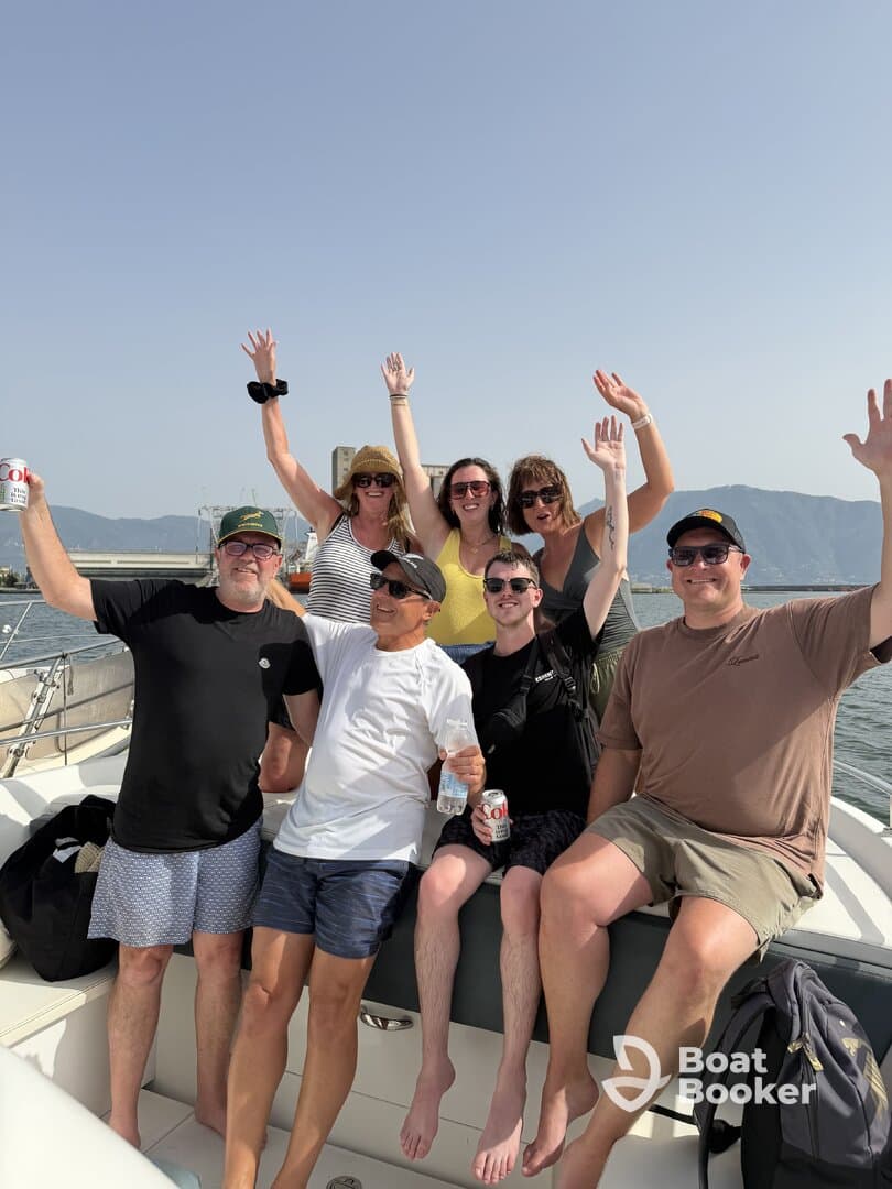 A lively group of friends celebrates on a boat, raising their hands in joy — perfect for memorable outings and fun on the water.