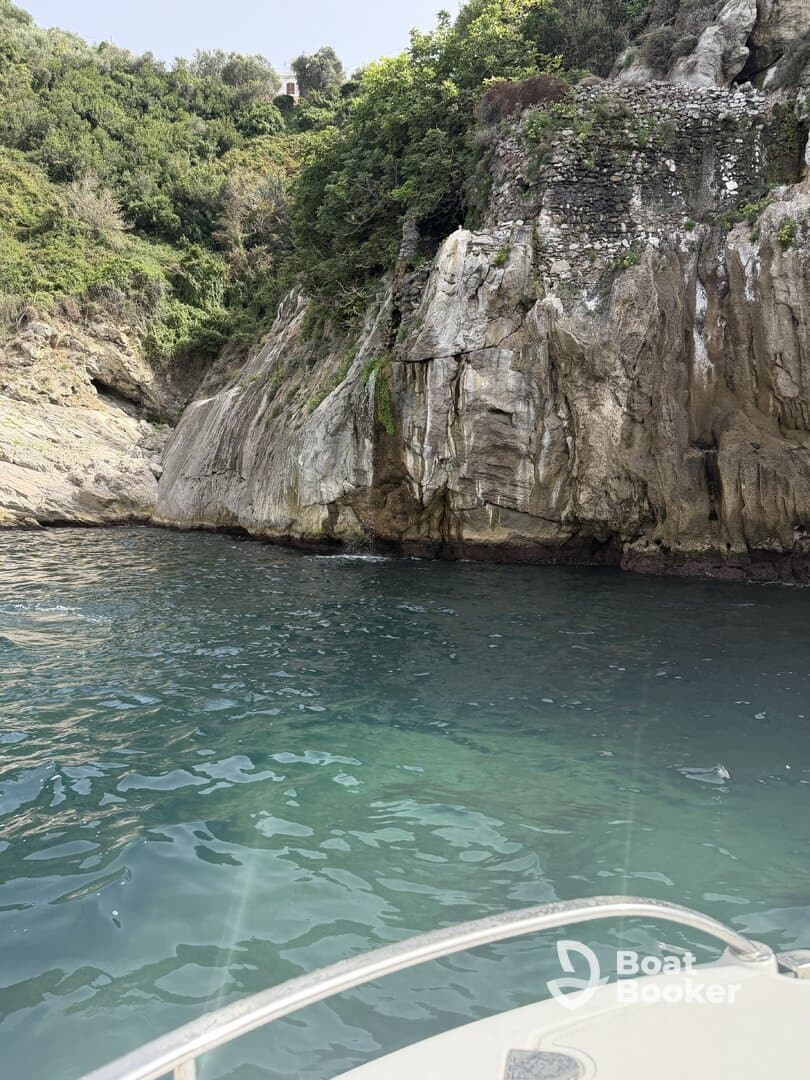 A picturesque view of a rocky coastline from a boat, showcasing the lush greenery and clear waters — ideal for exploring hidden coves and enjoying nature.