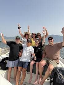 A lively group of friends celebrates on a boat, raising their hands in joy — perfect for memorable outings and fun on the water.