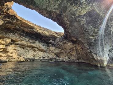A stunning view of a natural cave along the coastline, with crystal-clear waters inviting exploration — perfect for adventure seekers and nature lovers.