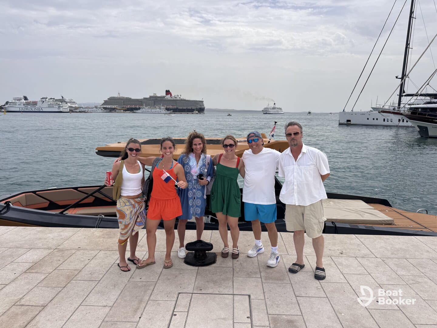 A cheerful group of friends poses together on the dock next to a stylish boat, capturing a memorable moment before their adventure on the water.